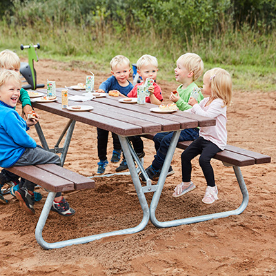 Des enfants sont assis sur une petite table de pique-nique dans une aire de jeux.